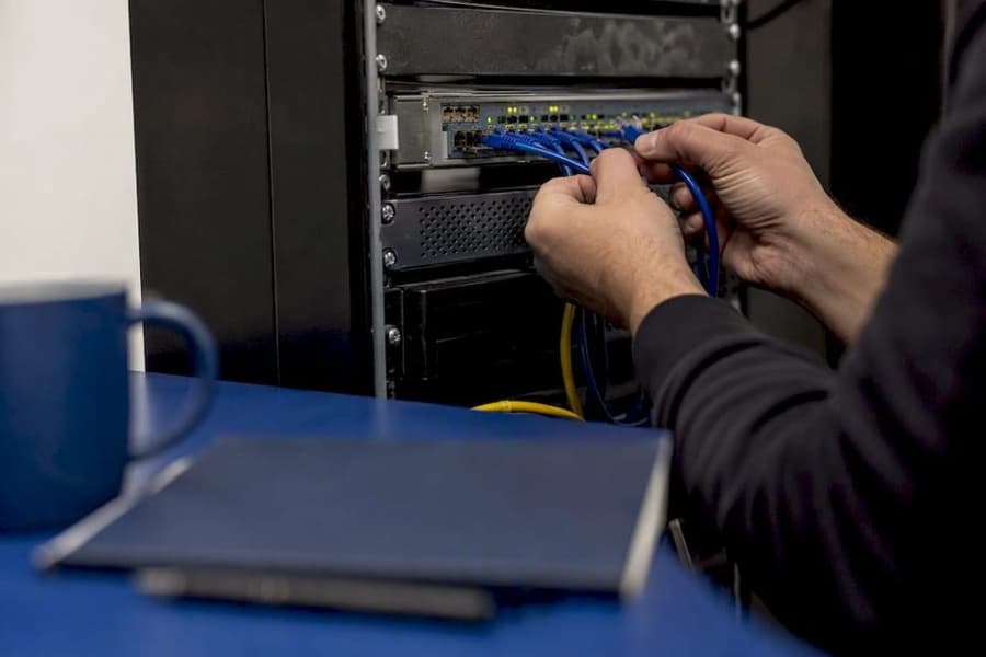 Mani che collegano cavi di rete all’interno di una sala server