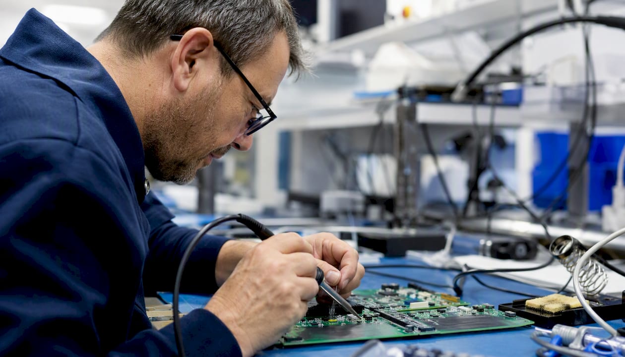 Mani esperte saldano componenti elettronici su una scheda PCB, dando vita ai circuiti.