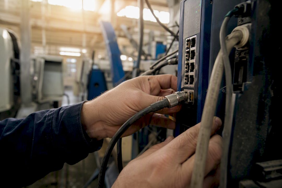 Tracciabilità commesse produzione: guida operativa per PMI 2 Mani che collegano un cavo di rete industriale